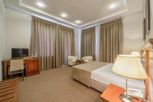 a hotel room with a bed and a desk and a television at Alarus Luxe Hotel in Odesa