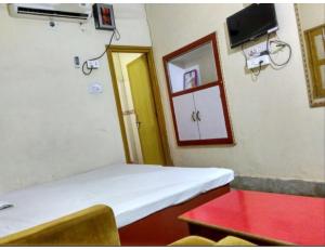 a room with a bed and a table and a window at Shivam Guest House, Gaya in Gaya