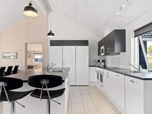 a kitchen with white cabinets and black counter stools at Holiday home Kappeln XXVI in Kappeln