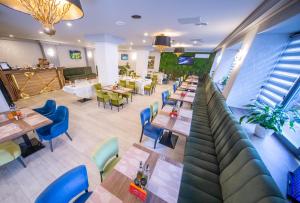 ein Restaurant mit Holztischen und blauen Stühlen in der Unterkunft Hotel Corvaris in Bukarest