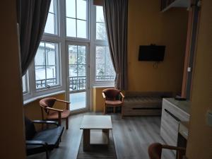 Willa Księżniczki Sopotu في سوبوت: غرفة معيشة مع أريكة وكراسي ونوافذ