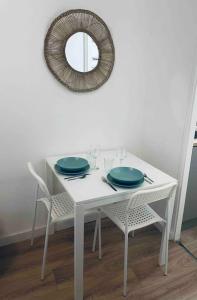 a white table with two blue plates and a mirror at Le P'tit Stud' in Castres