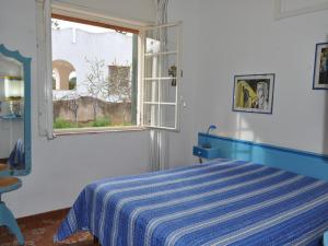 Un dormitorio con una cama azul y blanca y una ventana en CASE VACANZA PERLA DEL SUD, en San Vito lo Capo