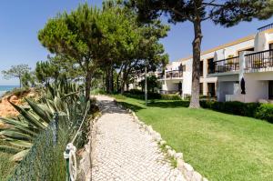 a walkway in front of a building with trees at Alfagar Village in Albufeira