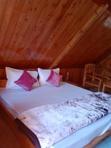 a bed in a room with a wooden ceiling at Forest View Cottage in Jibhi