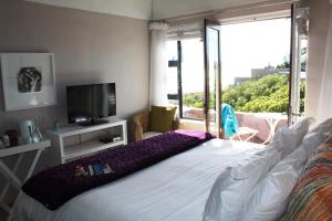 a bedroom with a bed with a television and a balcony at Absolute Beach Accommodation in Stompneusbaai