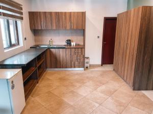 a kitchen with wooden cabinets and a tile floor at Sky Suites-Byblos Hotel Osu in Accra