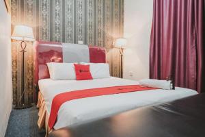 a bedroom with two beds with red and white at RedDoorz Plus @ Jalan Raden Intan Lampung in Bandar Lampung