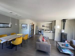 uma sala de estar e de jantar com uma mesa e cadeiras amarelas em Charmante Maison 400m du Golfe - Jacuzzi em Arradon