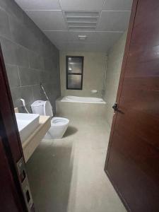 a bathroom with a toilet and a sink and a tub at Heart of Abu Dhabi - Wonder Balcony Room in Abu Dhabi