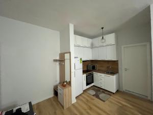 an empty kitchen with white cabinets and a refrigerator at SALA Apartment in Shkodër