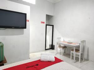 ein Raum mit einem Tisch und einem Fernseher an der Wand in der Unterkunft RedDoorz Syariah near Universitas Batanghari Jambi in Jambi + 31 Fotos