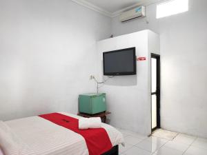 ein Schlafzimmer mit einem Bett und einem Fernseher an der Wand in der Unterkunft RedDoorz Syariah near Universitas Batanghari Jambi in Jambi