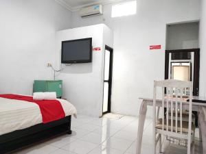ein Schlafzimmer mit einem Bett und einem Fernseher an der Wand in der Unterkunft RedDoorz Syariah near Universitas Batanghari Jambi in Jambi