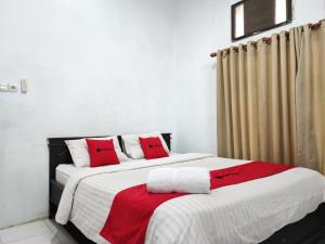 2 Betten in einem Zimmer mit roten Kissen darauf in der Unterkunft RedDoorz Syariah near Universitas Batanghari Jambi in Jambi