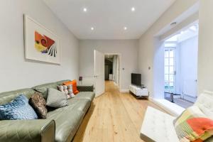 a living room with a green couch and wooden floors at 2 Bed Flat South Kensington in London