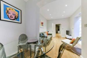 a living room with a glass table and chairs at 2 Bed Flat South Kensington in London