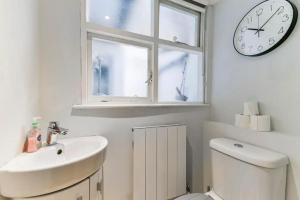a bathroom with a sink and a clock on a window at 2 Bed Flat South Kensington in London