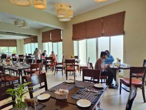 ein Restaurant mit Tischen und Personen, die an Tischen sitzen in der Unterkunft Hotel Grand Park Barishal in Barishal