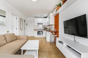 a living room with a couch and a large flat screen tv at Bright Amadores Seaview Apartment in Puerto Rico de Gran Canaria