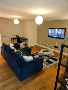 a living room with a blue couch and a flat screen tv at LONDON FRESHAir BREATHE APARTMENT in London