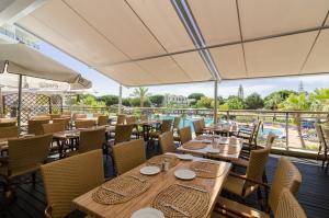 un restaurant avec des tables et des chaises ainsi qu'une piscine dans l'établissement Alfagar Aparthotel, à Albufeira