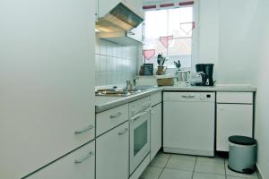 cocina con armarios blancos, fregadero y ventana en Holiday complex Wenkendorf, Fehmarn-Wenkendorf, en Lemkendorf