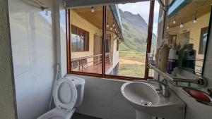 baño con aseo y lavabo y ventana en Xúa Vừ Homestay en Mèo Vạc