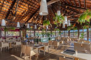 un restaurante con mesas, sillas y macetas en Elba Sara Beach & Golf Resort en Caleta de Fuste