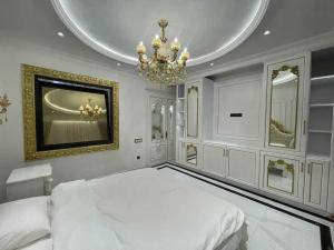 een slaapkamer met een wit bed en een kroonluchter bij Premium Residences by Renowned Builders in Tasjkent