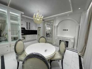een eetkamer met een tafel en stoelen en een kroonluchter bij Premium Residences by Renowned Builders in Tasjkent