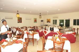 a restaurant with tables and a woman standing in the middle at Grand Hotel Juba in Juba