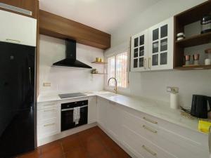 uma cozinha com armários brancos e um frigorífico preto em Exclusive House with Incredible Mountain Views em Alcaucín