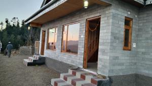 a house being constructed with a sunset in the background at Rai Desh Cottages in Shimla