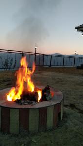 a fire pit in a field with flames at Rai Desh Cottages in Shimla