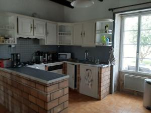 une cuisine avec des placards blancs et un comptoir en briques dans l'établissement Maison en Vendée avec Piscine, à Corpe