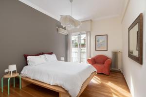 Athenian Apartment in Kolonaki في أثينا: غرفة نوم بسرير وكرسي احمر