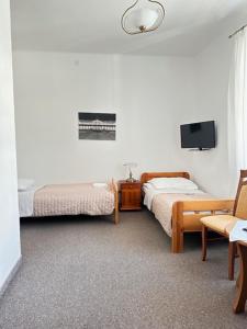 a bedroom with two beds and a tv and a chair at Boży Dar in Krynica Zdrój