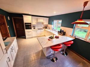 a kitchen with white cabinets and red stools at Lark Rise Holiday Home Glenbeigh in Glenbeigh