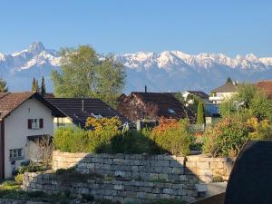 um grupo de casas com montanhas ao fundo em Ferienwohnung am Tor zum Berner Oberland em Steffisburg