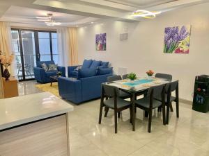 a living room with a table and a blue couch at Riverside 3 B/Rm Nairobi in Nairobi