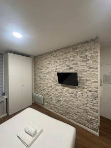 een slaapkamer met een bakstenen muur en een tv bij Charming & welcoming flat next to Tost beautiful places in Paris Museum of modern art Quai Branly Museum in Parijs