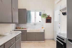 cocina con armarios grises, fregadero y ventana en Athenian Apartment in Kolonaki en Atenas