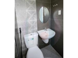 a bathroom with a white toilet and a sink at Ricres Hometel R3 in Babak