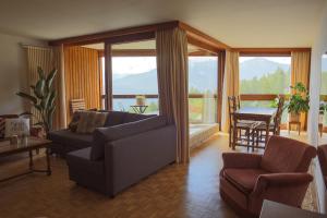 een woonkamer met een bank en stoelen en een balkon bij Mountain View Apartment with Parking & Fast WiFi in Crans-Montana