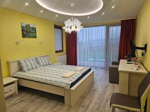 1 dormitorio con cama, escritorio y lámpara de araña en Relax Srednogorska Panorama, en Smolsko
