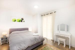 een witte slaapkamer met een bed en een bureau bij Large terrace, sea view, private parking included in Beausoleil