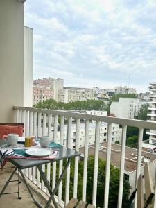 a table on a balcony with a view of a city at Chambre tout confort, spacieuse, calme et lumineuse avec balcon in Paris