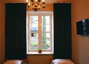 a window in a bedroom with green curtains and a chandelier at Sami Swoi Kluki 42 in Kluki