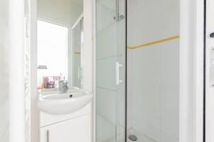 ein weißes Bad mit einem Waschbecken und einer Dusche in der Unterkunft Appartement Vintage Le Bon Marché - III in Paris